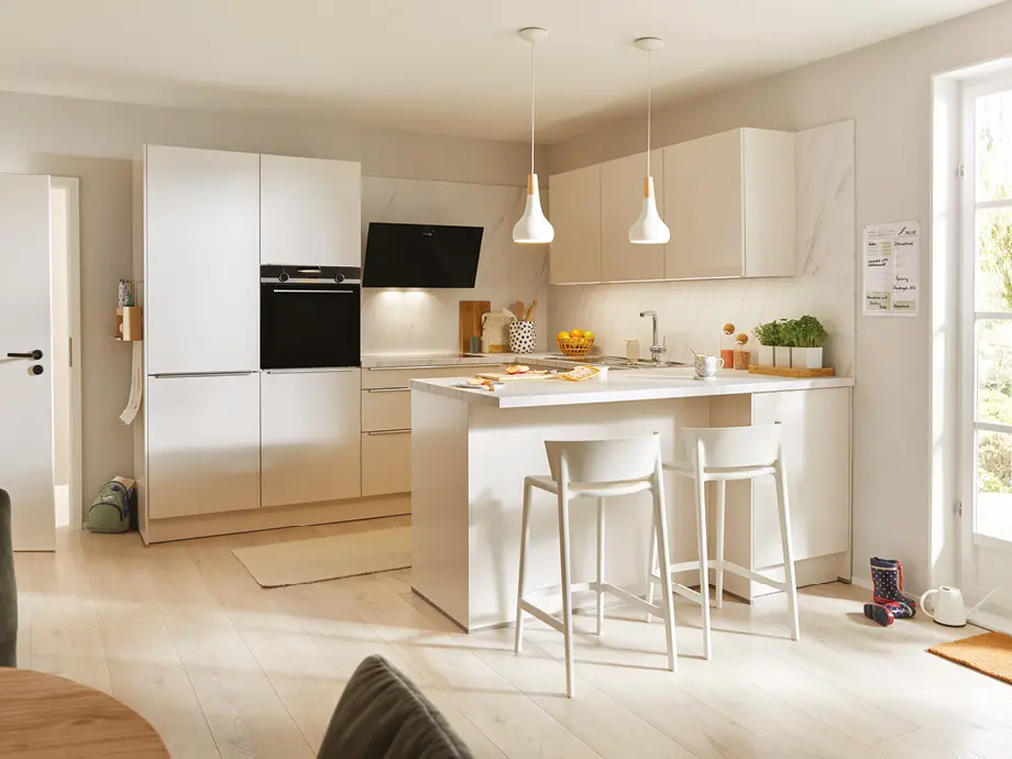 Moderne Wohnlandschaft in Grau mit Recamiere und Kissen, platziert vor bodentiefen Fenstern mit Blick ins Grüne. Stilvolles Sofa im hellen Wohnzimmer mit Teppich und Couchtisch als Inspiration für modernes Wohnen.